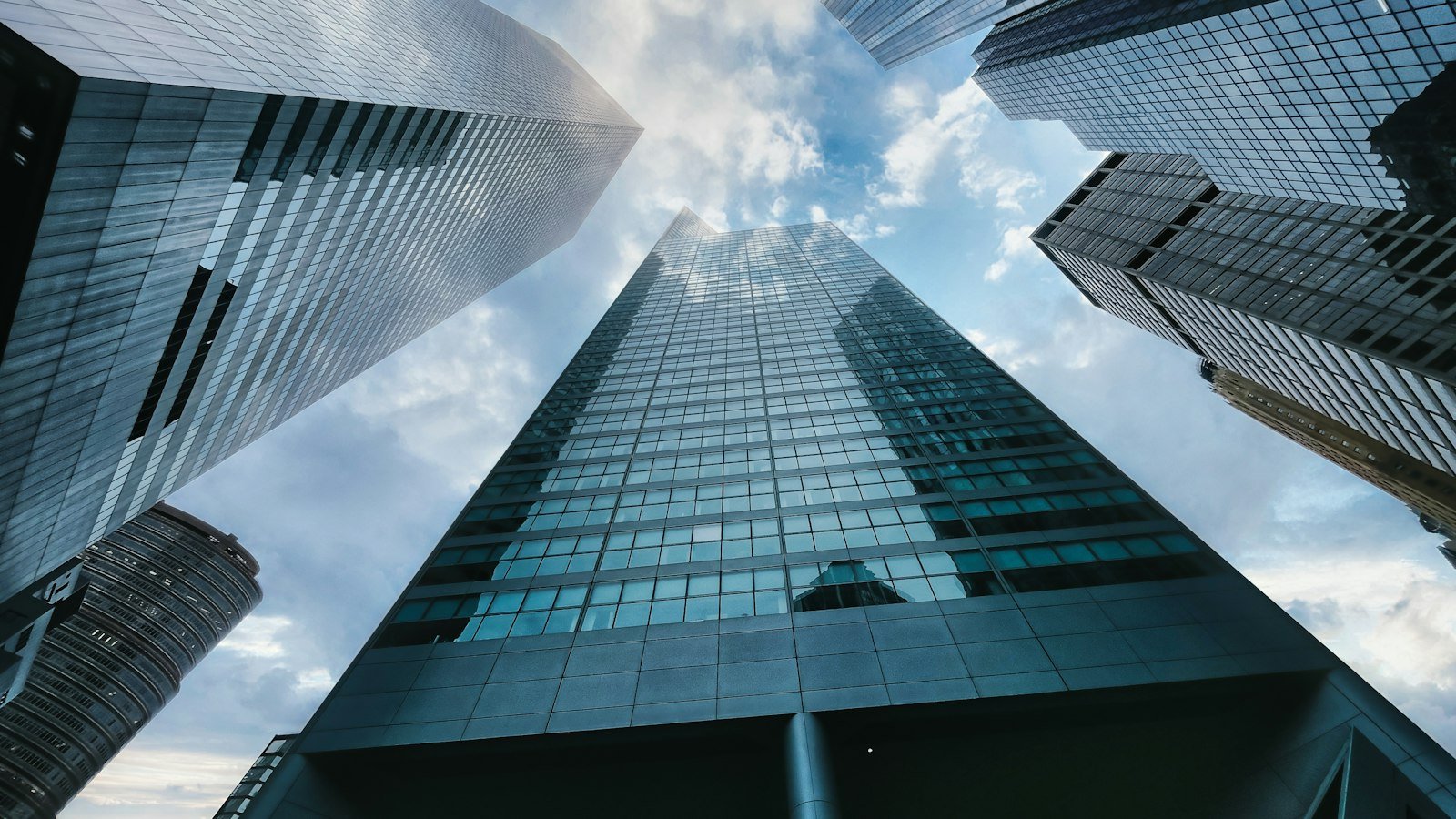 Low-angle view of a bank skyscraper in midtown Manhattan under white clouds